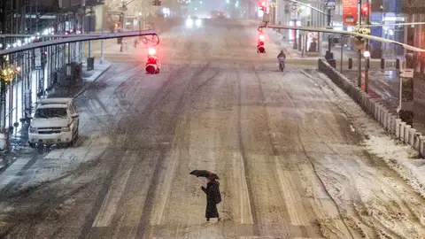 A woman crosses a street near Manhattan's Grand Central during a snowfall in New York City on Feb. 22, 2026. (Photo by CHARLY TRIBALLEAU/AFP via Getty Images)