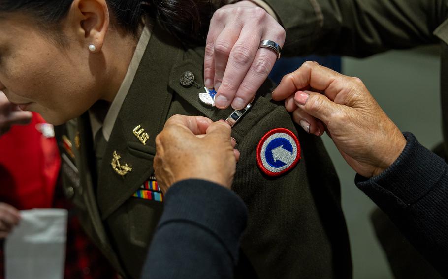 Hands pin rank insignia on the shoulder of a soldier.